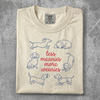 Cream t-shirt with blue dachshund illustrations and "less meanies more weenies" text.