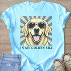 Light blue t-shirt with a smiling, sunglasses-wearing golden retriever graphic and text "IN MY GOLDEN ERA".