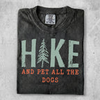 Dark t-shirt with "Hike and Pet All the Dogs" text and a pine tree graphic.