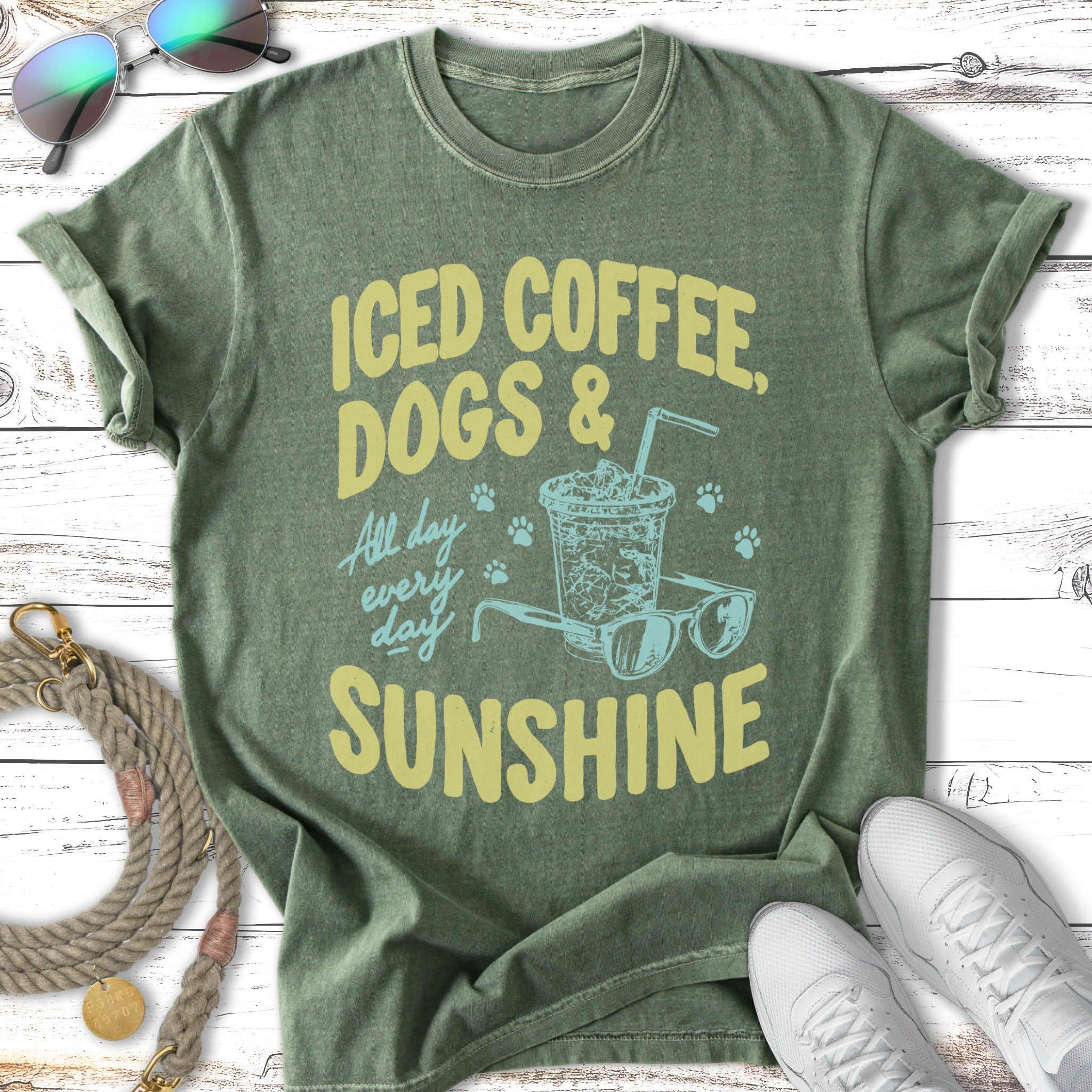 Green t-shirt with "ICED COFFEE, DOGS & SUNSHINE" text and illustrated iced coffee and sunglasses.