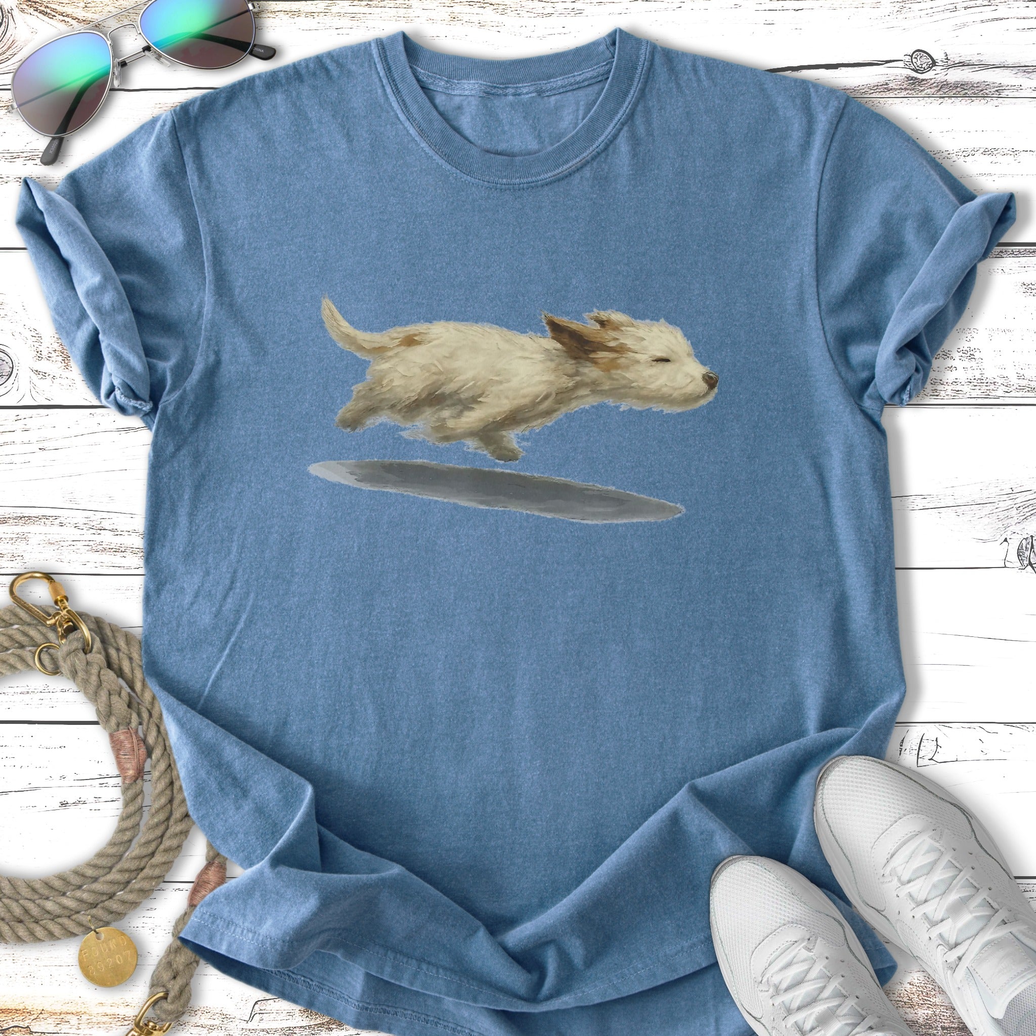 White terrier puppy leaping over a puddle on a blue t-shirt.