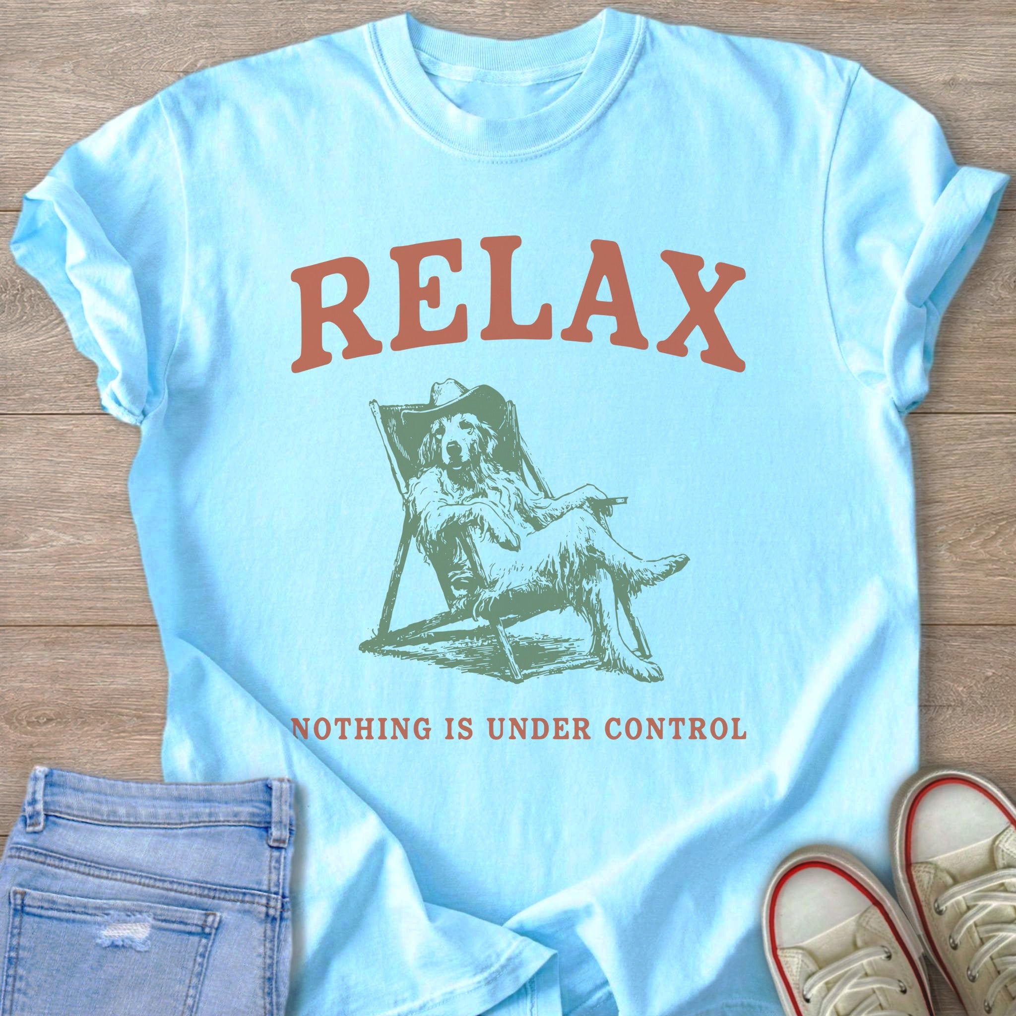Light blue t-shirt with "RELAX" above a dog wearing a cowboy hat relaxing in a chair.