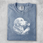 Blue t-shirt with white line art of a golden retriever sniffing a dandelion.