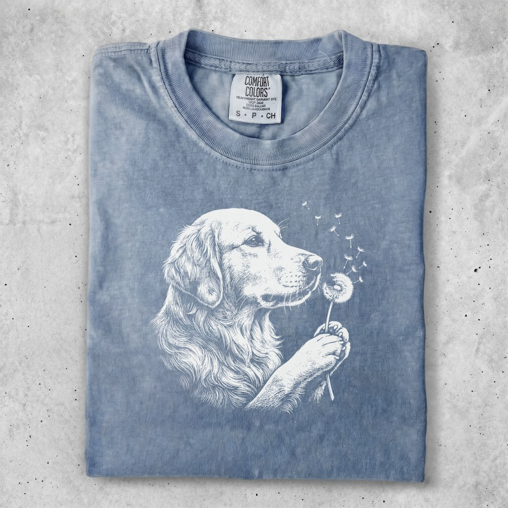 Blue t-shirt with white line art of a golden retriever sniffing a dandelion.