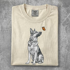 Cream t-shirt with a black and white German Shepherd looking at an orange butterfly.