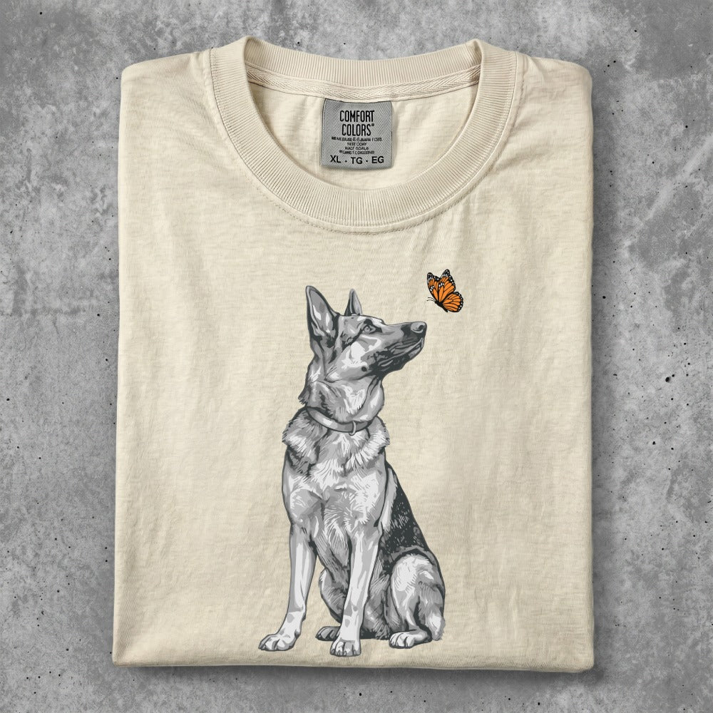 Cream t-shirt with a black and white German Shepherd looking at an orange butterfly.