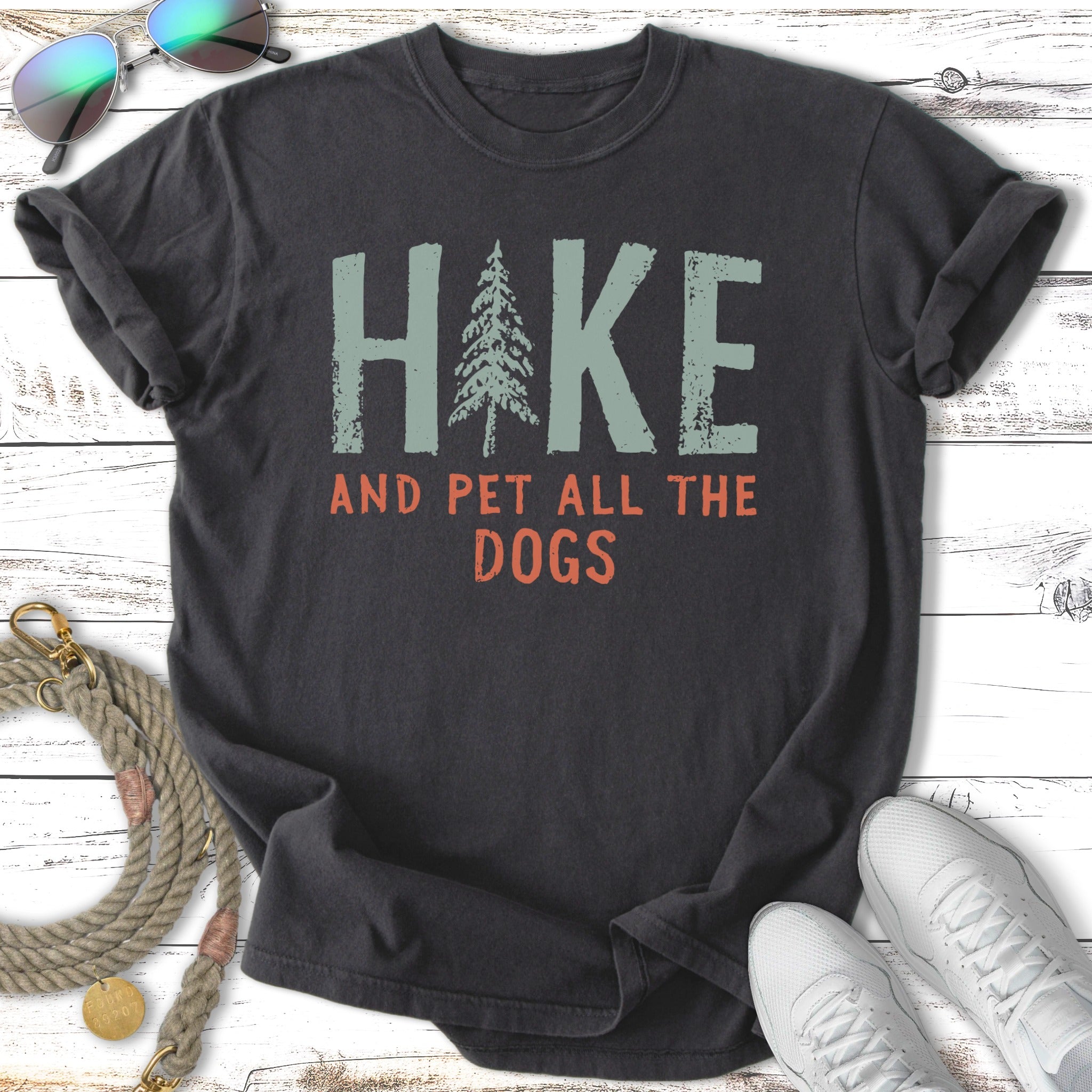 Dark t-shirt with "HIKE AND PET ALL THE DOGS" text and a pine tree graphic.