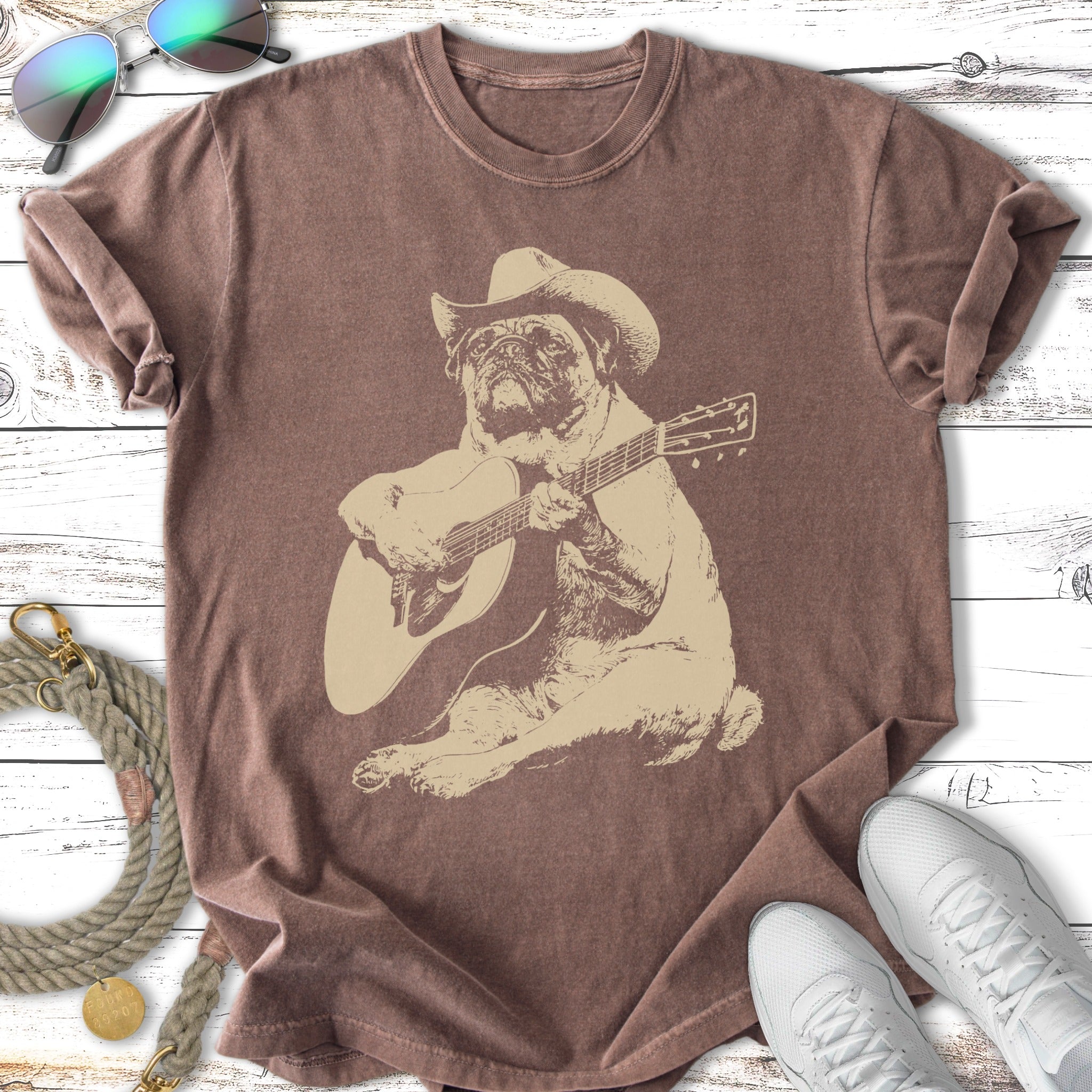 Pug wearing a cowboy hat plays a guitar on a vintage-style t-shirt.