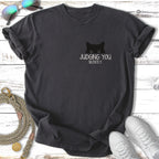 Black t-shirt with a cat's eyes peeking from pocket, text "JUDGING YOU SILENTLY."