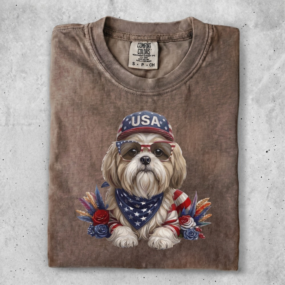 Dog wearing sunglasses and a bandana, with "USA" hat and patriotic decorations.