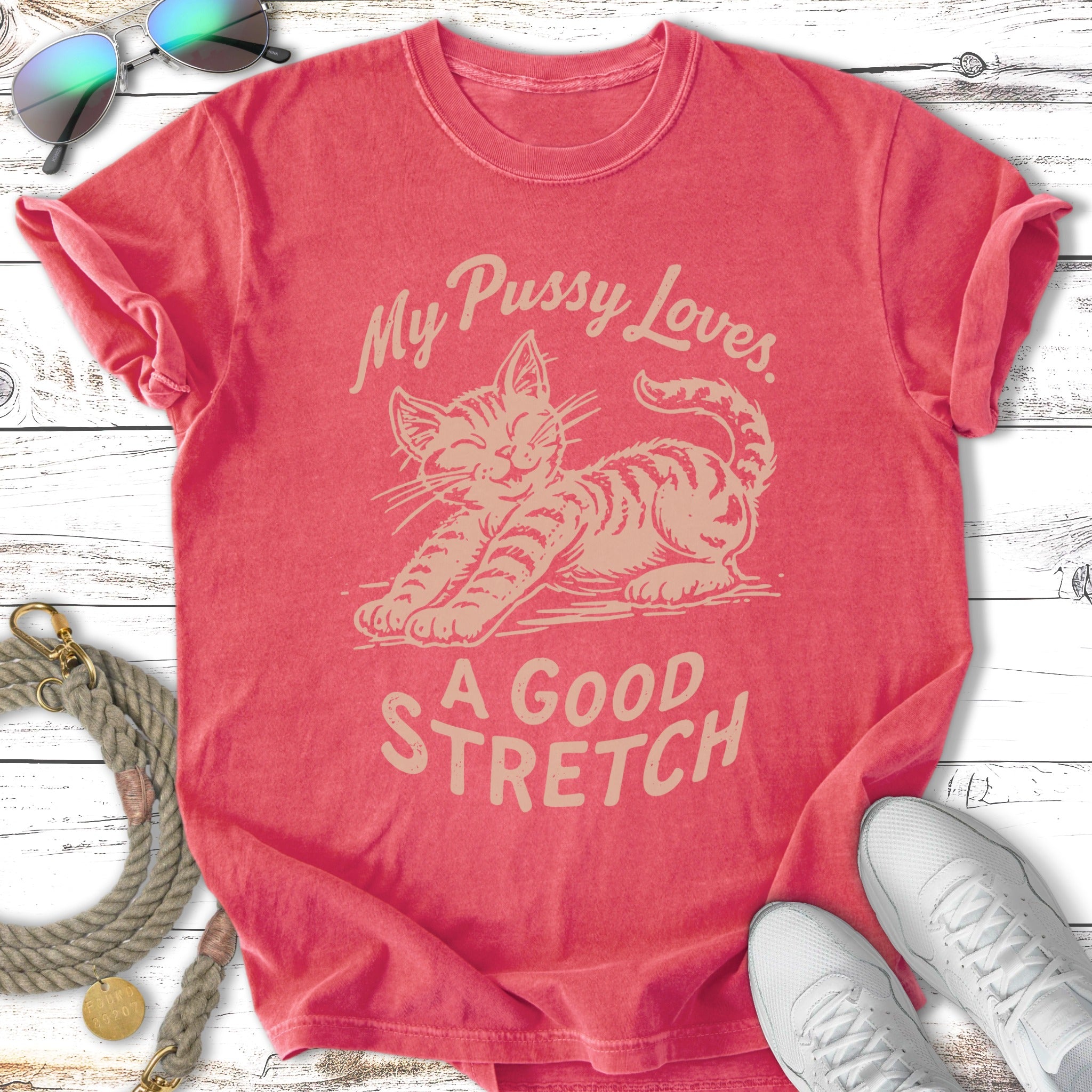 Coral t-shirt with a cartoon cat stretching and text "My Pussy Loves. A Good Stretch."