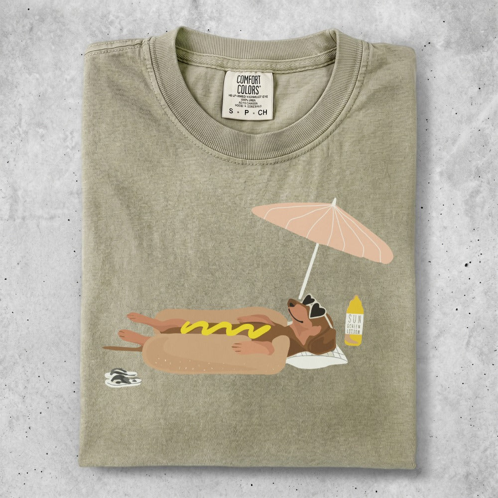 T-shirt with a dog wearing sunglasses, relaxing under a beach umbrella.