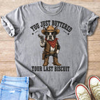 Gray t-shirt with a cartoon Boston Terrier cowboy holding a gun and the text "YOU JUST BUTTERED YOUR LAST BISCUIT".