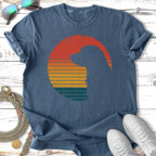 Silhouette of a dog's head within a sunset circle on a blue t-shirt.