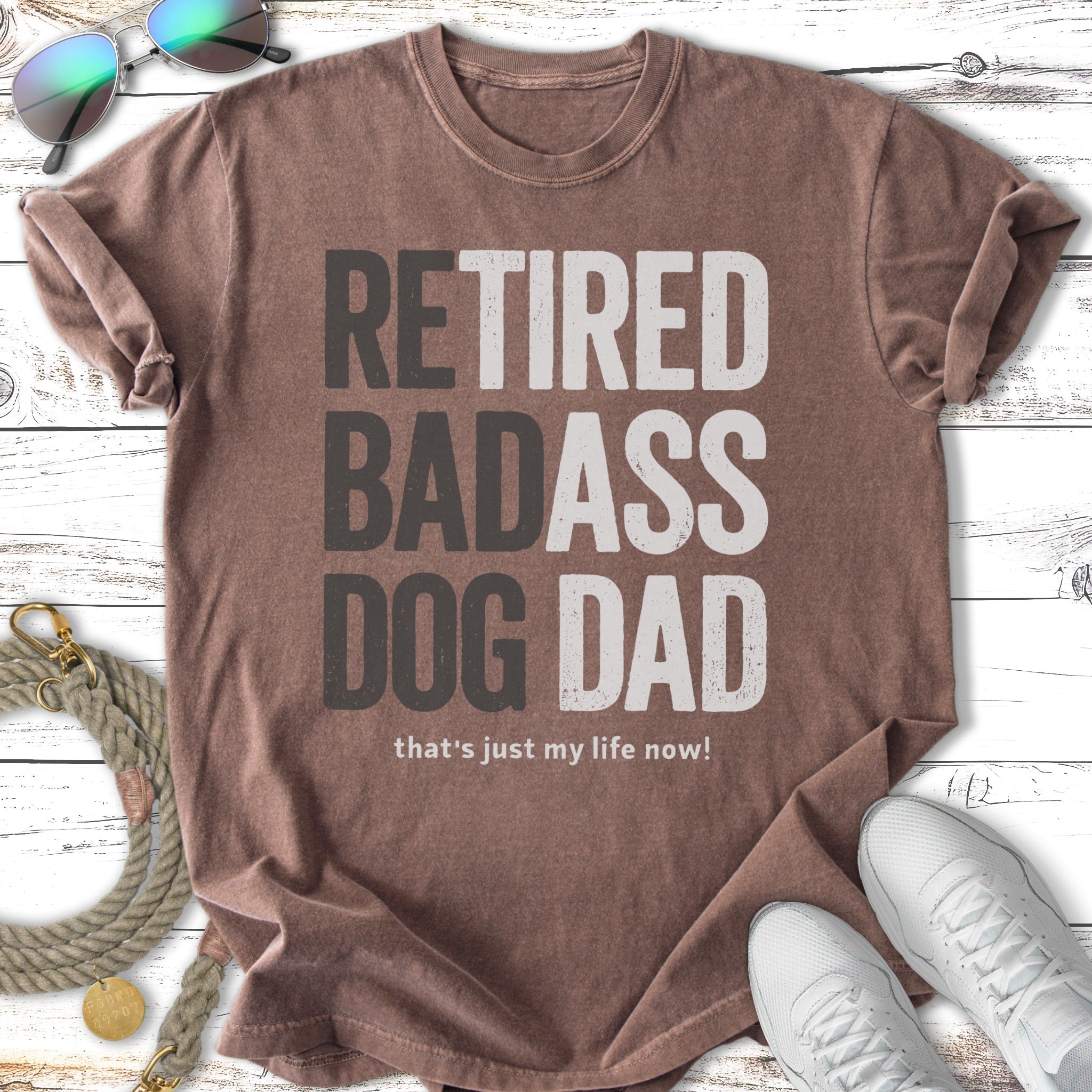 Retired Badass Dog Dad text on a brown t-shirt with sunglasses and sneakers.