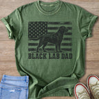 Green t-shirt with black lab silhouette on distressed American flag and text "BLACK LAB DAD".