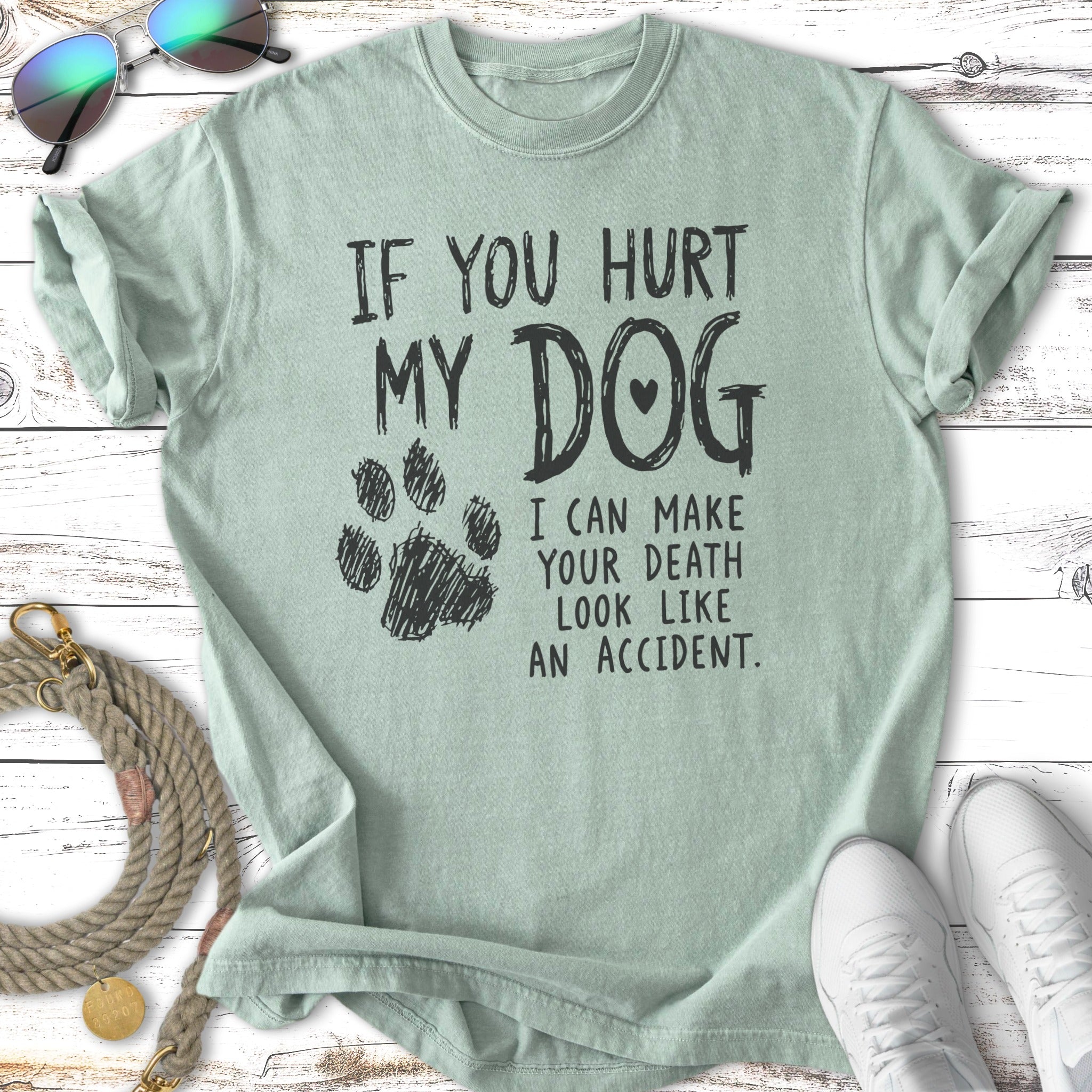 Pale green t-shirt with paw print and bold text "If you hurt my dog I can make your death look like an accident."