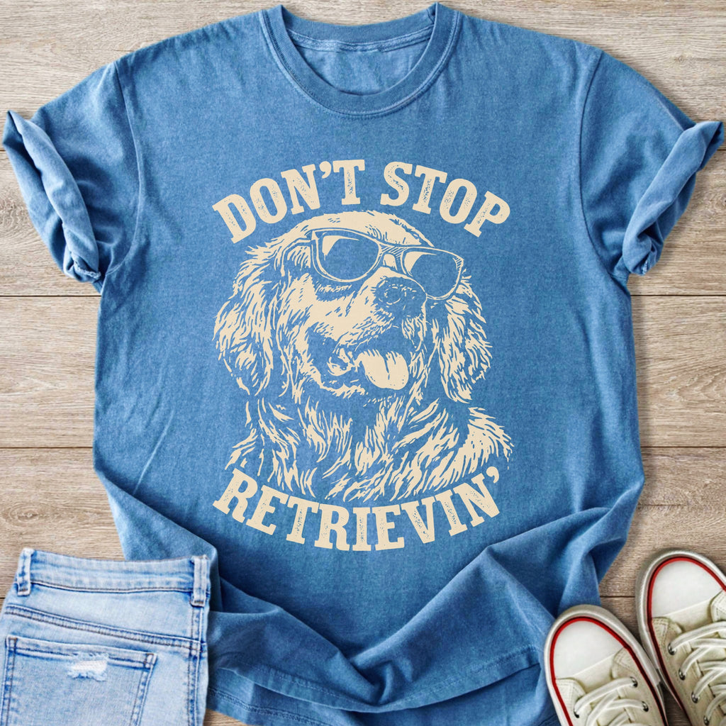 Blue t-shirt with cream graphic of a dog wearing sunglasses and text "DON'T STOP RETRIEVIN'".