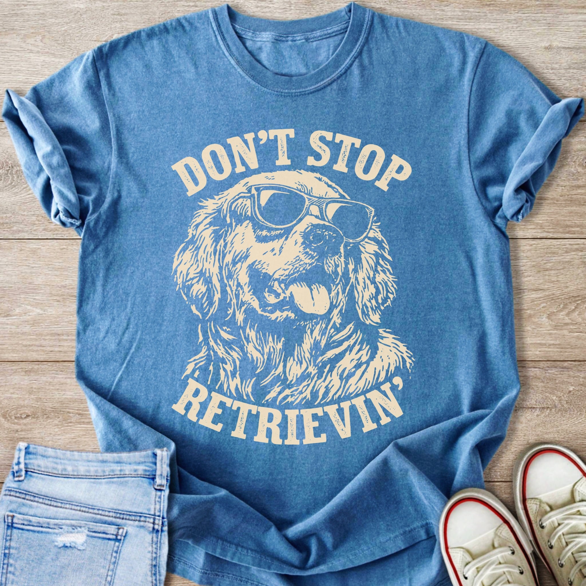 Blue t-shirt with cream graphic of a dog wearing sunglasses and text "DON'T STOP RETRIEVIN'".
