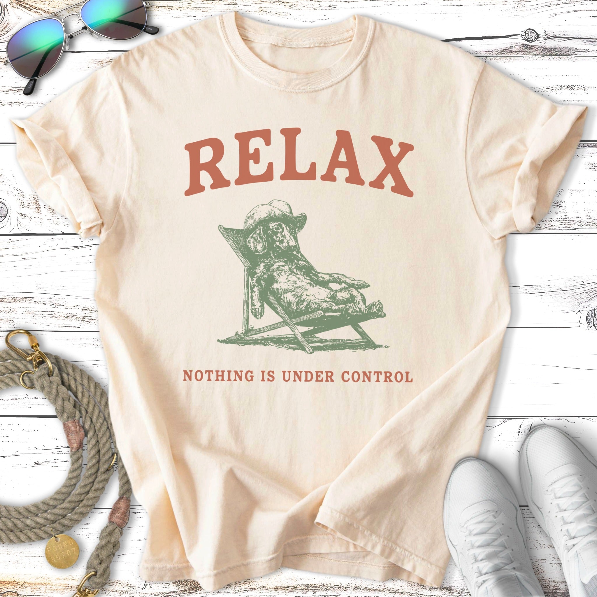 Cream t-shirt with dog on lounge chair and text "RELAX NOTHING IS UNDER CONTROL".