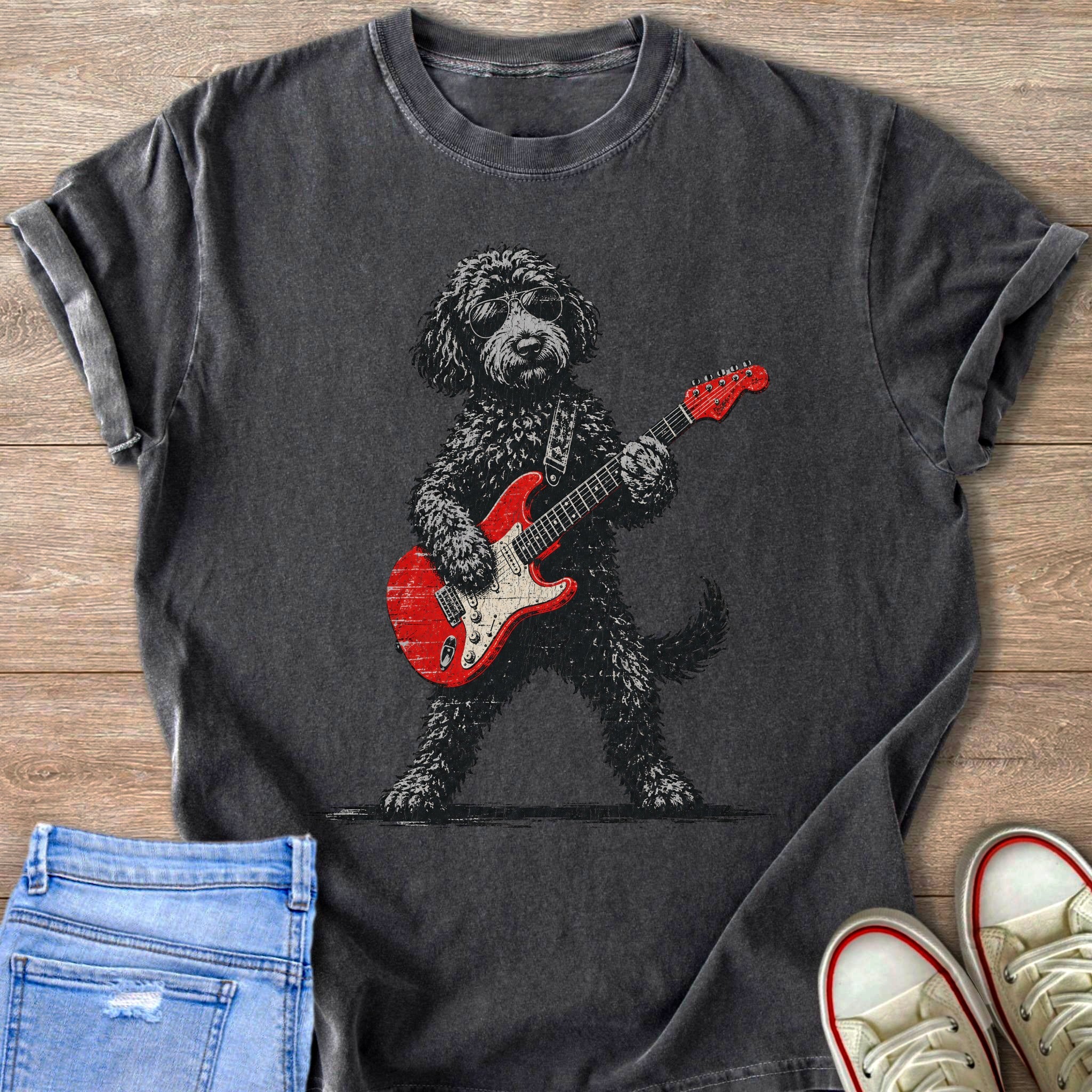 Black dog wearing sunglasses playing a red electric guitar on a dark t-shirt.