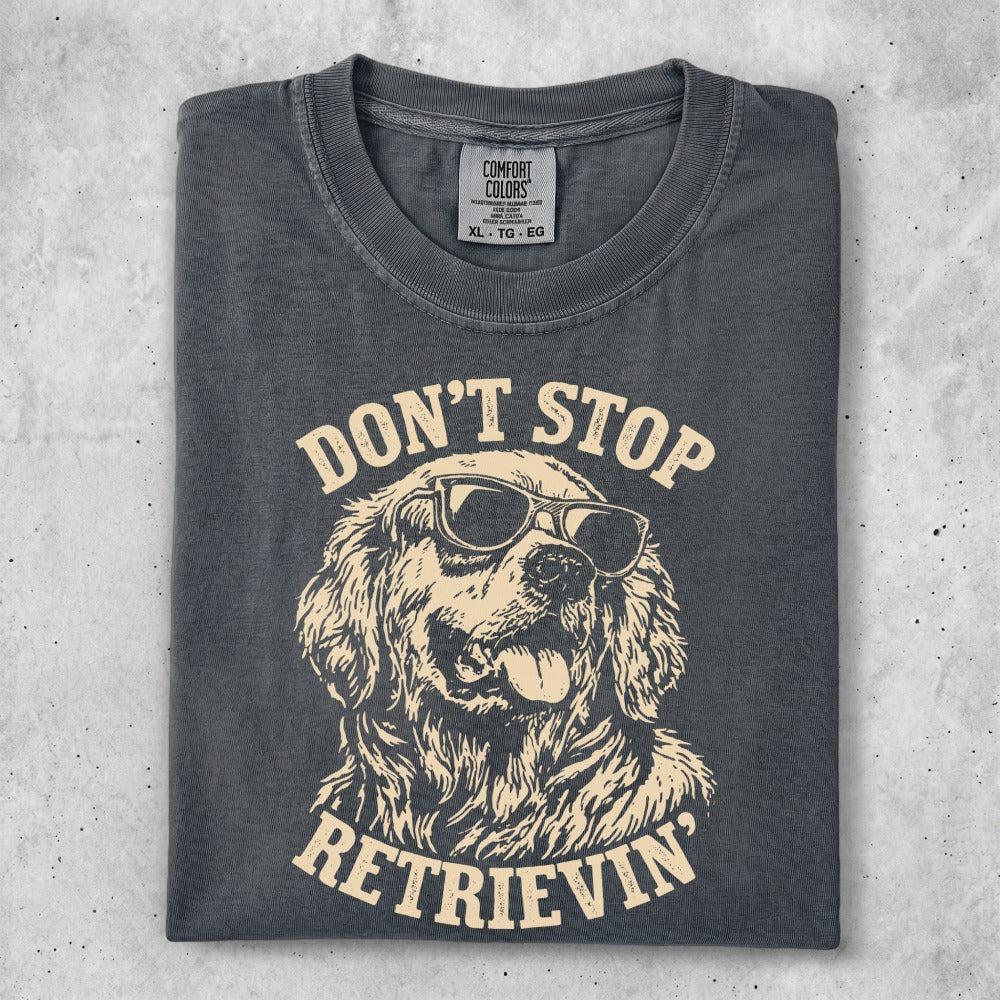 Dark grey t-shirt with graphic of Golden Retriever wearing sunglasses and text "DON'T STOP RETRIEVIN'".