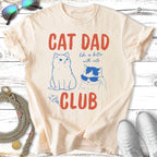 Cream t-shirt with blue cartoon cats and "CAT DAD CLUB" text.