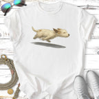 Cream-colored puppy running with a shadow beneath it, on a white t-shirt.