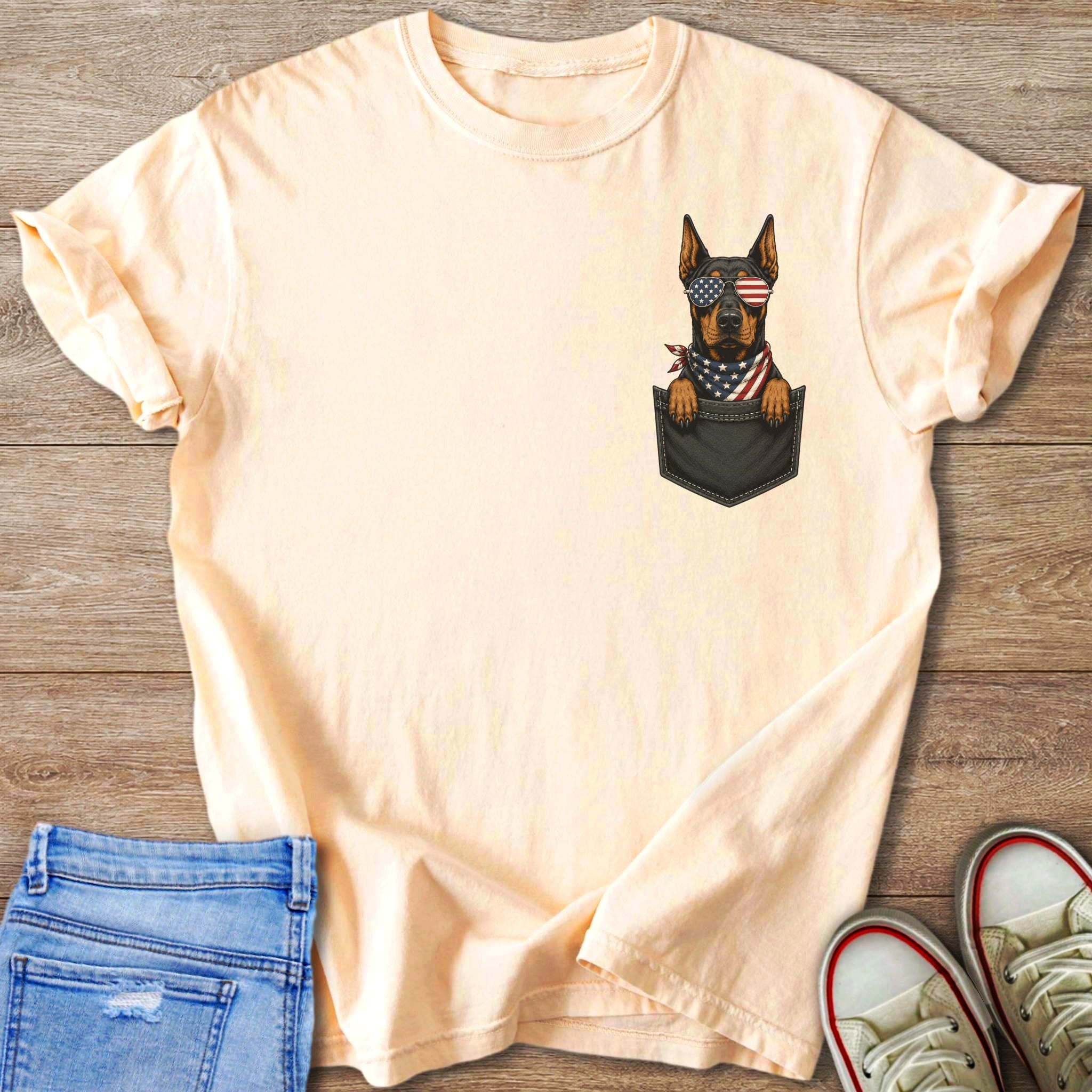 Peach t-shirt with a dog in a pocket wearing American flag sunglasses and bandana.