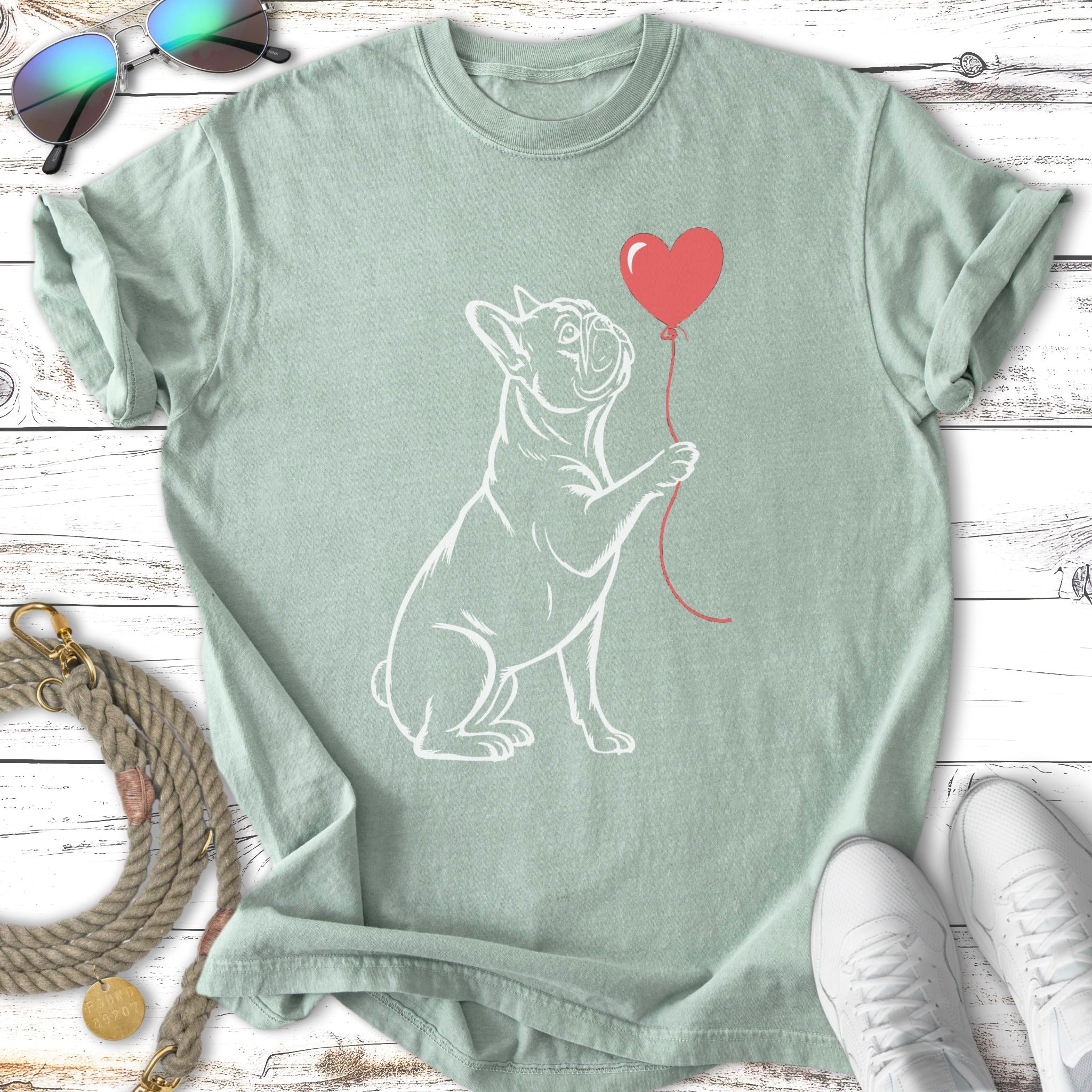 White outline of a French bulldog holding a red heart balloon.