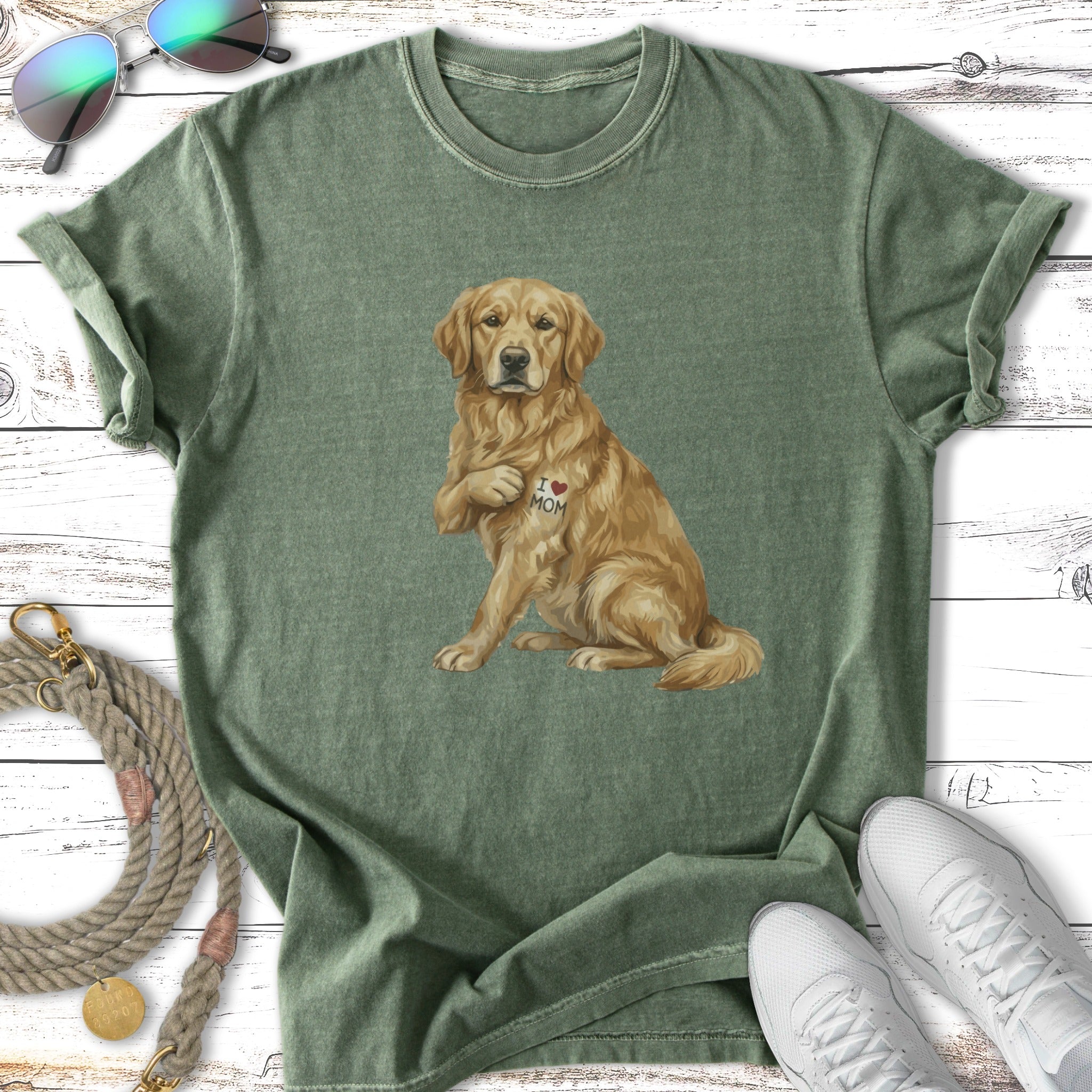 Golden Retriever wearing an "I LOVE MOM" heart tattoo sits on a green t-shirt.