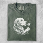 Green t-shirt with white graphic of a golden retriever blowing dandelion seeds.