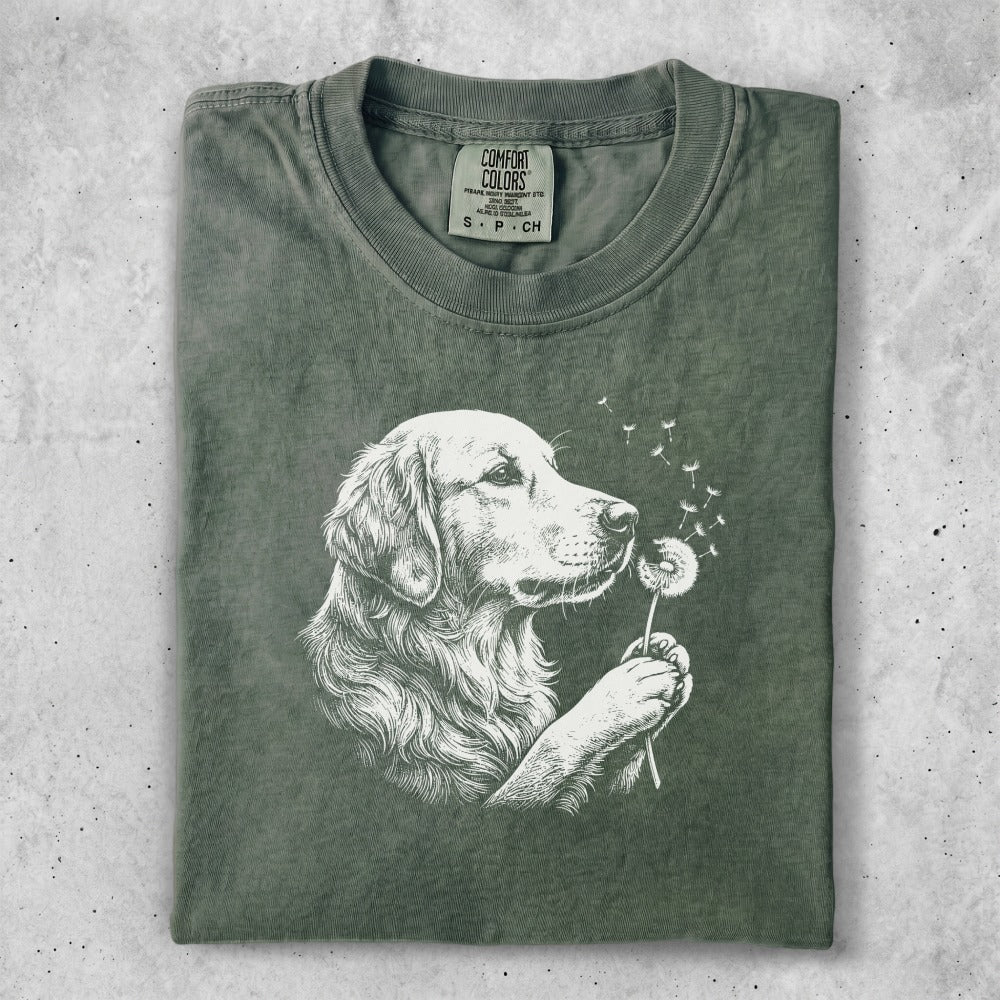 Green t-shirt with white graphic of a golden retriever blowing dandelion seeds.