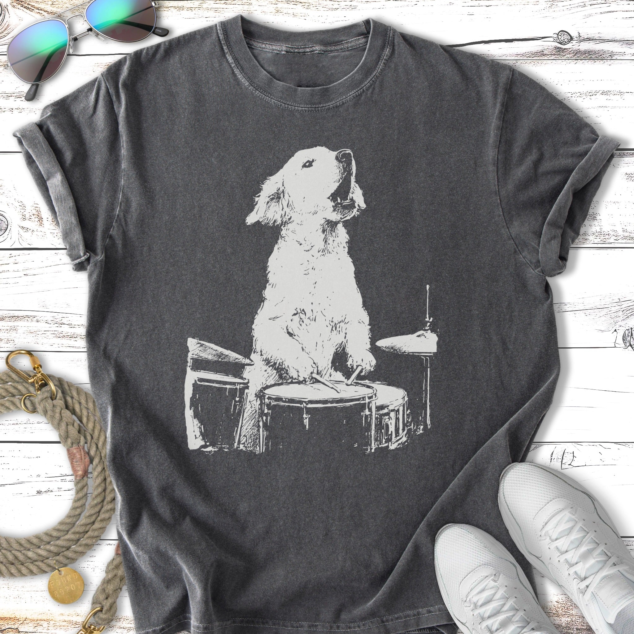 White dog playing drums on a dark gray t-shirt.