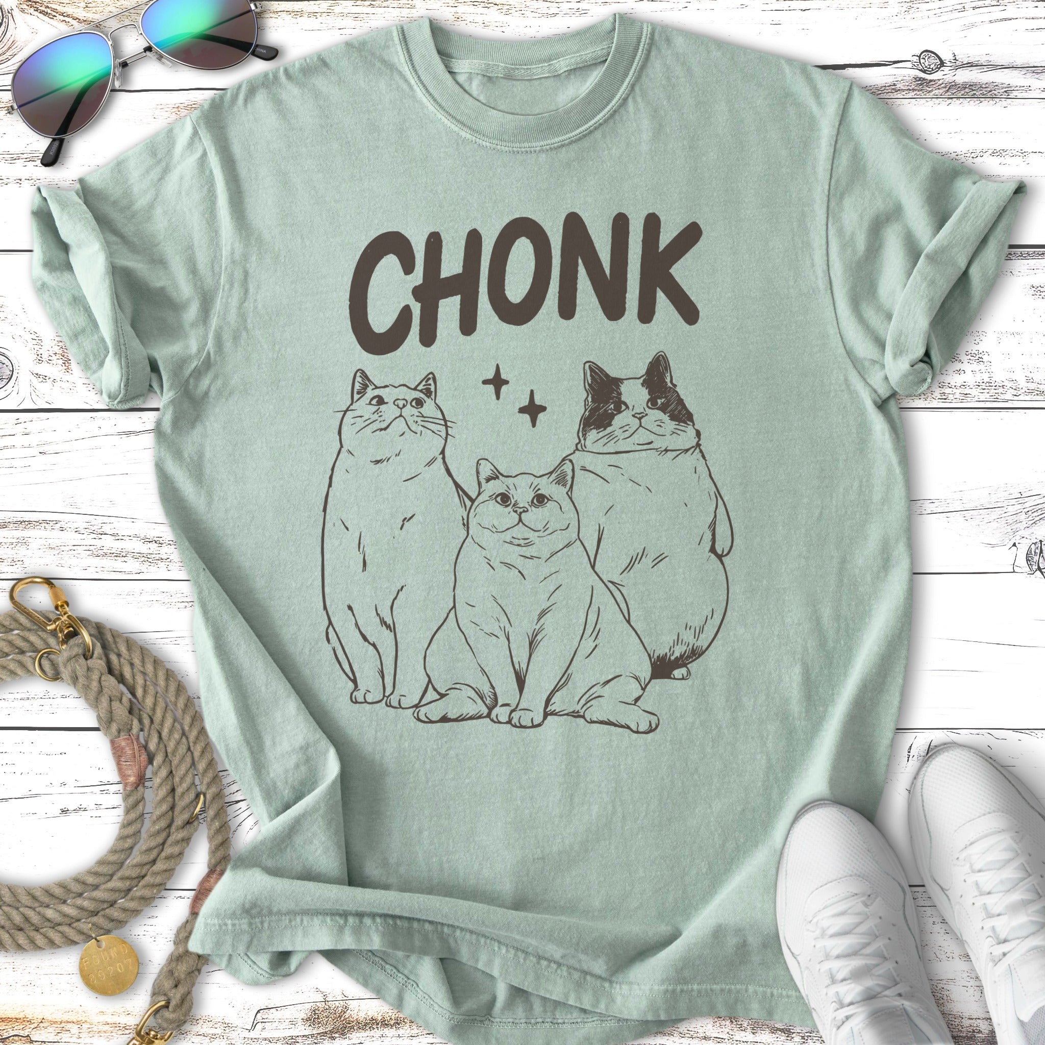 Three line art cats with "CHONK" text above them on a light green t-shirt.