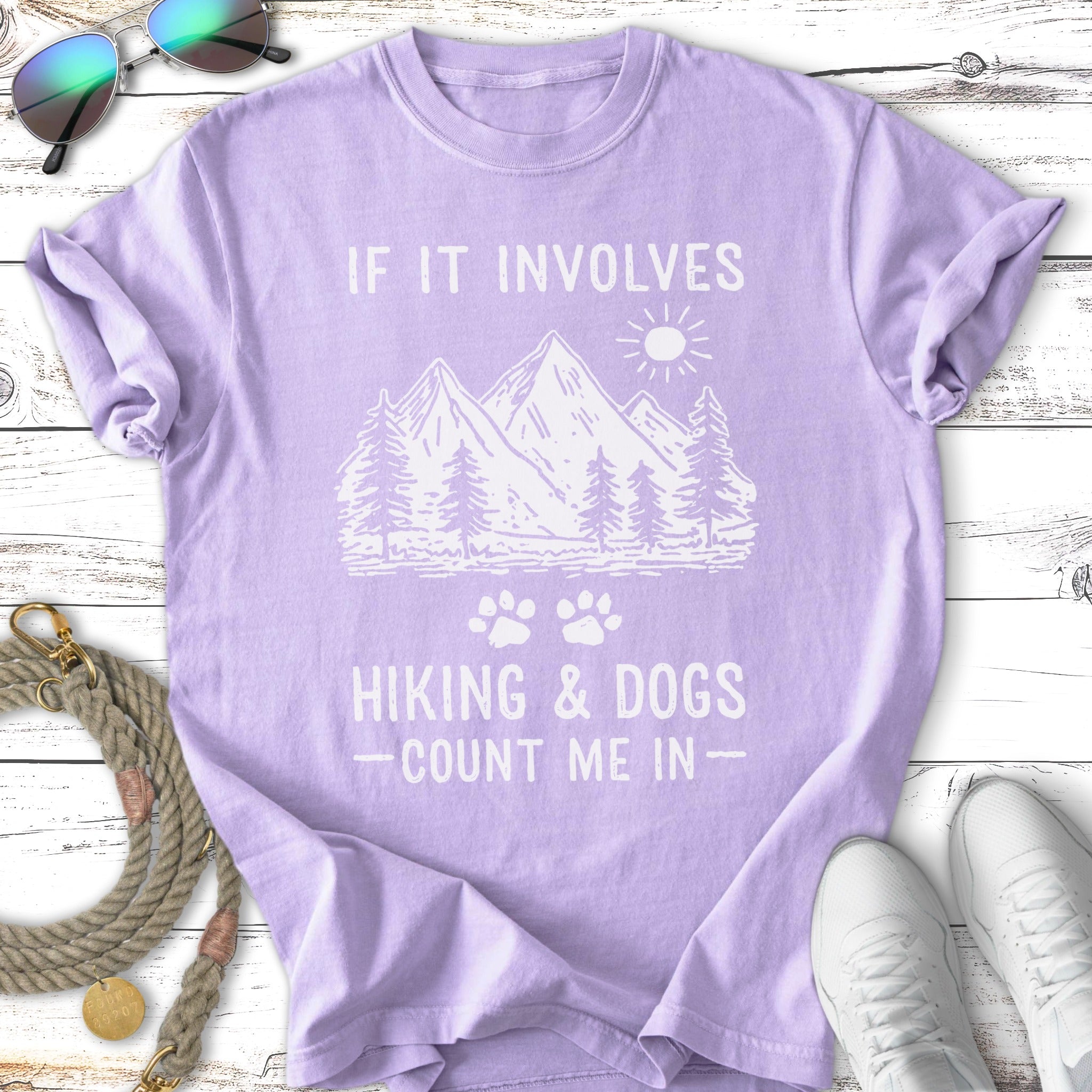 Purple t-shirt with mountains, trees, and text "If it involves hiking & dogs - count me in".