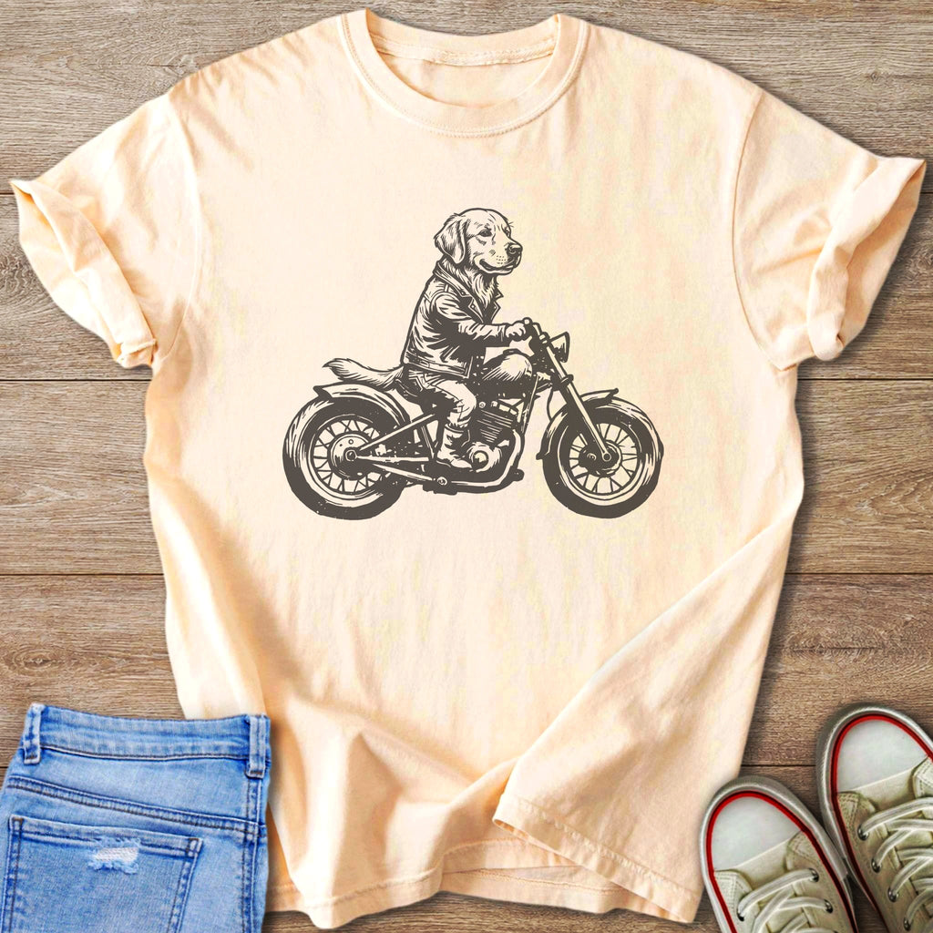 Black and white sketch of a dog wearing a jacket riding a motorcycle on a peach t-shirt.