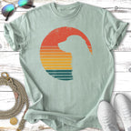 Silhouette of a dog within a retro sunset circle on a light green t-shirt.