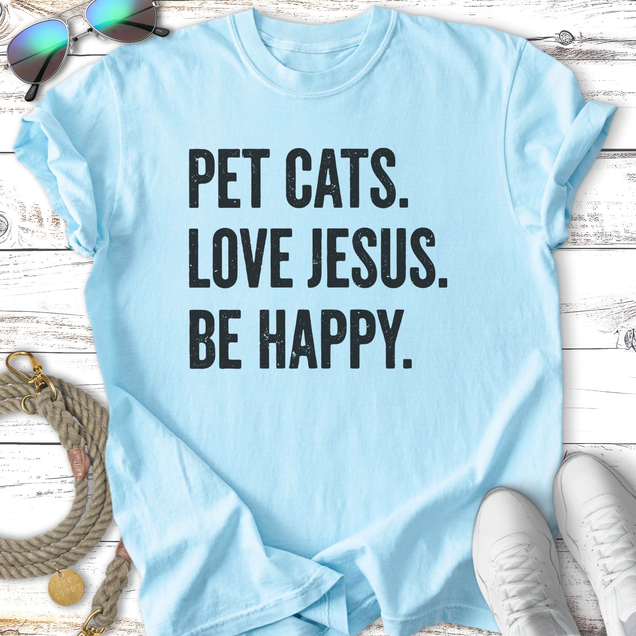 Light blue t-shirt with "PET CATS. LOVE JESUS. BE HAPPY." text.