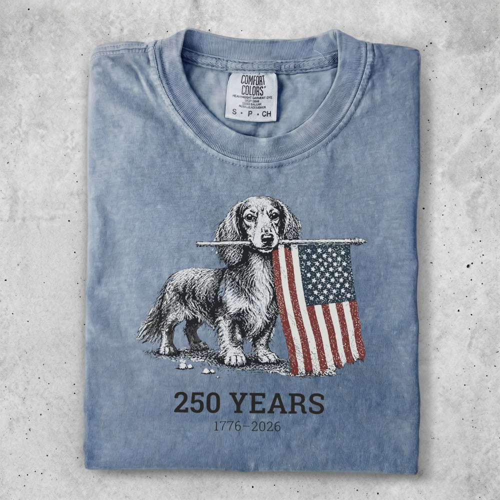 Dachshund holding an American flag with "250 YEARS 1776-2026" text.