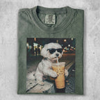 White dog wearing sunglasses drinks iced coffee.
