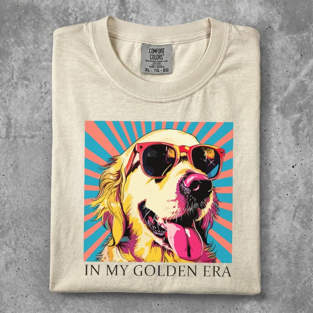 Cream t-shirt with a golden retriever wearing sunglasses, tongue out, against a colorful background.