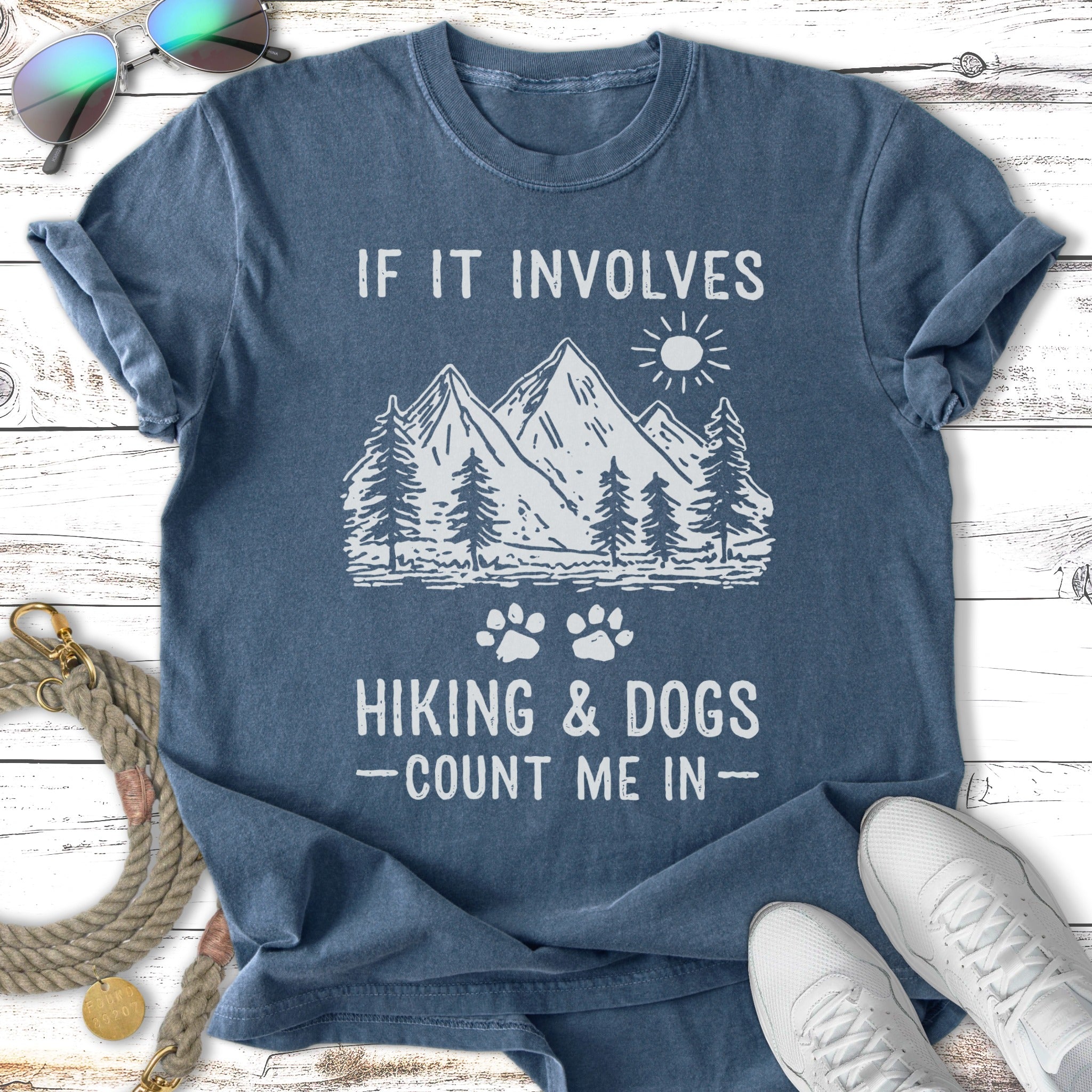 T-shirt with mountains, sun, paw prints, and text "If It Involves Hiking & Dogs - Count Me In".
