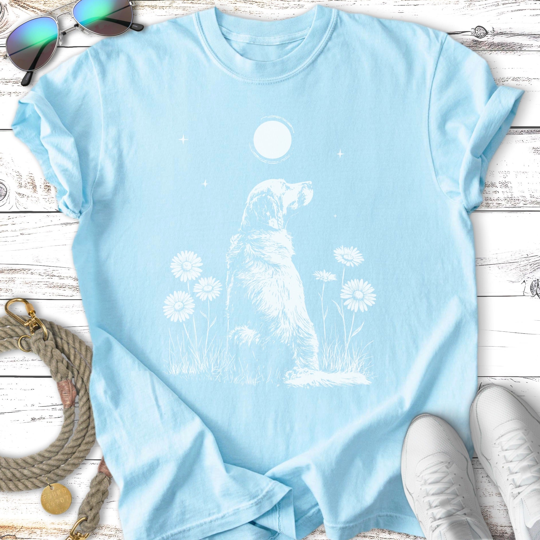 Light blue t-shirt with white silhouette of a dog and daisies under a moon.