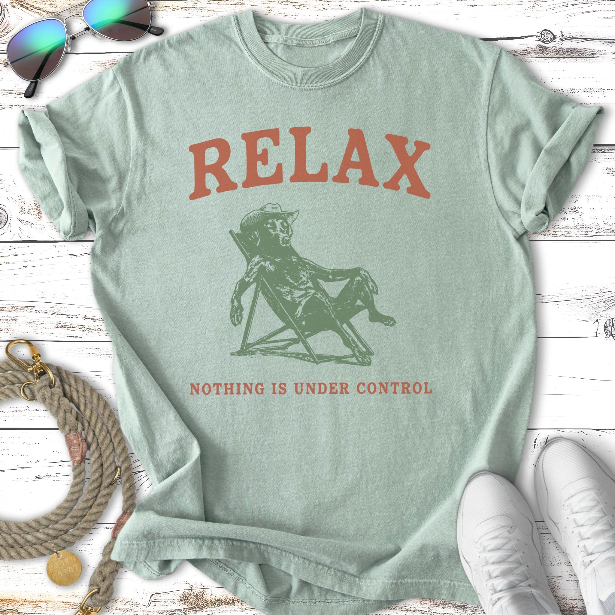 Green t-shirt with a cartoon dog in a chair, text reads "RELAX NOTHING IS UNDER CONTROL".