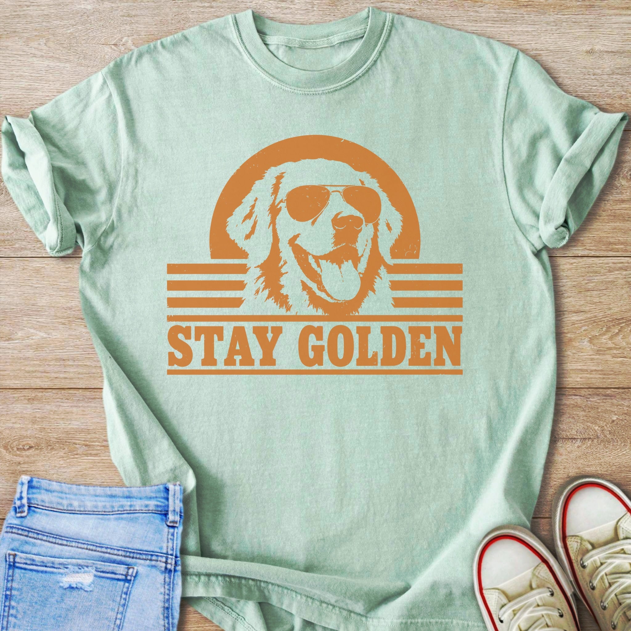 Light green t-shirt with orange graphic of golden retriever wearing sunglasses and text "STAY GOLDEN".