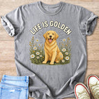 Golden retriever in field of daisies with text "LIFE IS GOLDEN" on gray t-shirt.