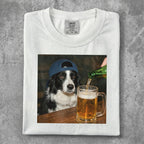 Black and white dog wearing a blue baseball cap drinks from a beer mug.