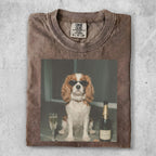 Dog wearing sunglasses sits by a champagne bottle and flute.