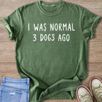 Green t-shirt with white text reading "I WAS NORMAL 3 DOGS AGO".